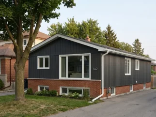 Etobicoke mid-century bungalow modernized with dark metal vertical siding installation, seamless aluminum eavestrough replacement, and matching soffit and fascia by Maxima Aluminum. Serving Mimico, Long Branch, Alderwood, The Kingsway, Islington, and Humber Bay lakefront properties.