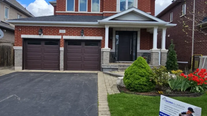 Eavestrough and downspout work on a red-brick home in Mississauga, with the Maxima lawn sign beside the driveway.